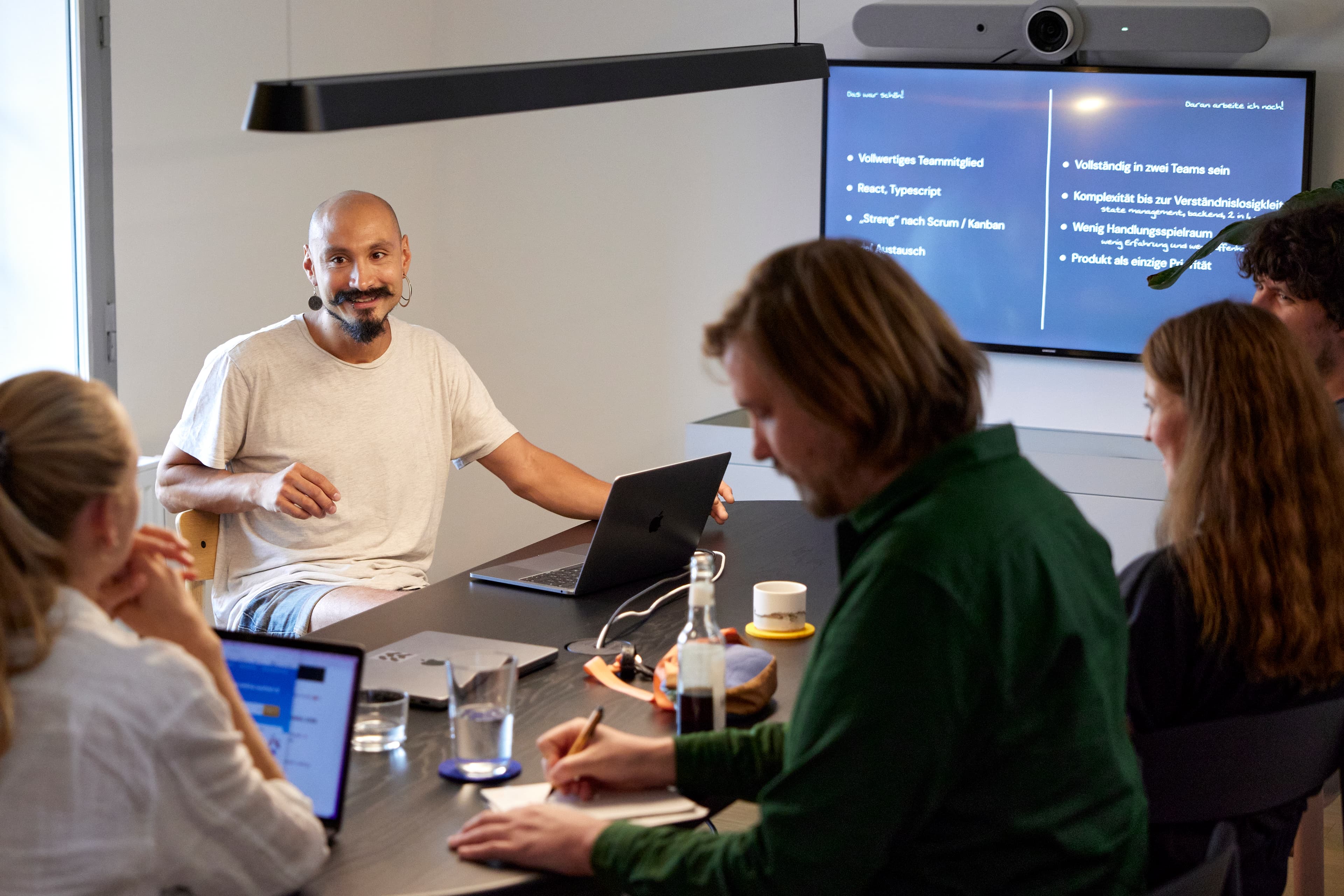 Fünf Personen am Tisch im Besprechungsraum mit Fokus auf einer der Personen